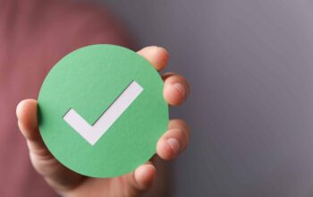 A,Hand,Holding,A,Green,Paper,With,The,Checkmark,Sign